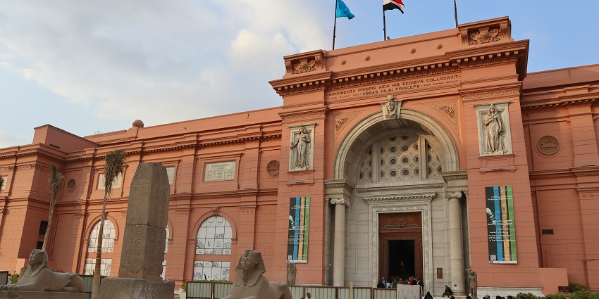 The front view of the Egyptian Museum features a crowd of tourists near the entrance.