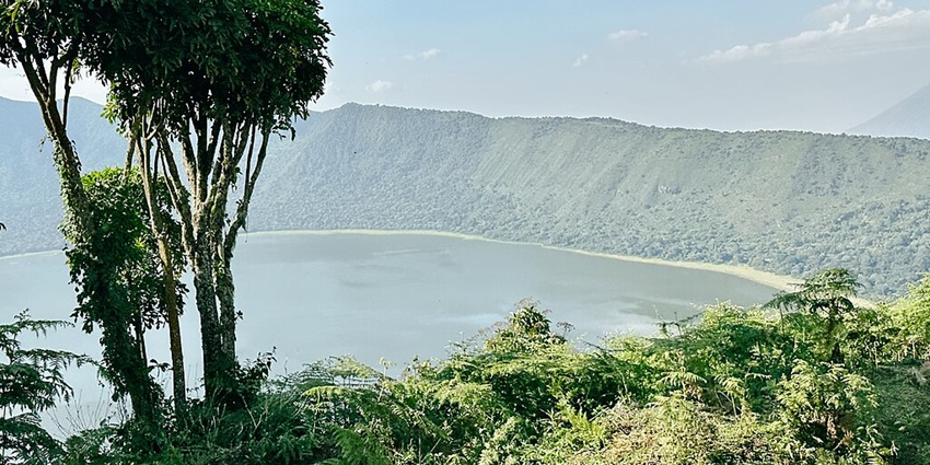 Empakaai crater from top and crater filled with water surrounded by green cliffs.