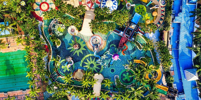 An image of a colourful water park featuring exciting rides, swimming pits and play zones