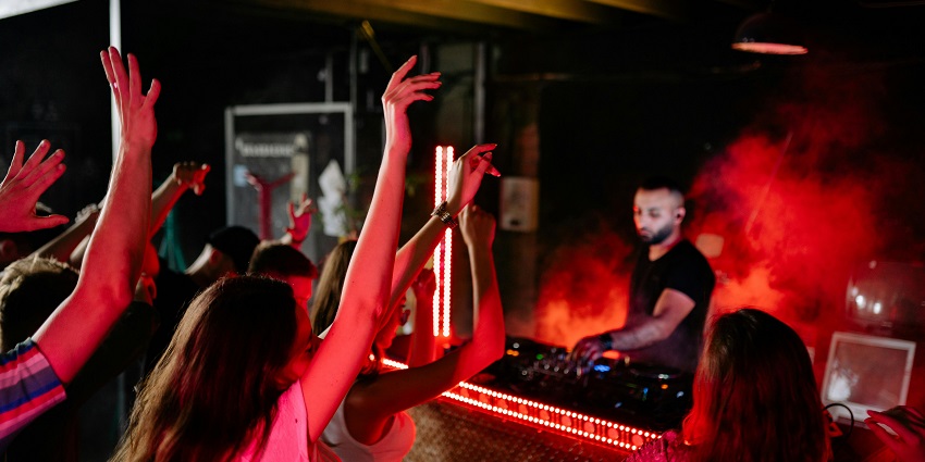 A group of people dancing joyfully in a vibrant club setting with colourful lighting in Los Angeles.
