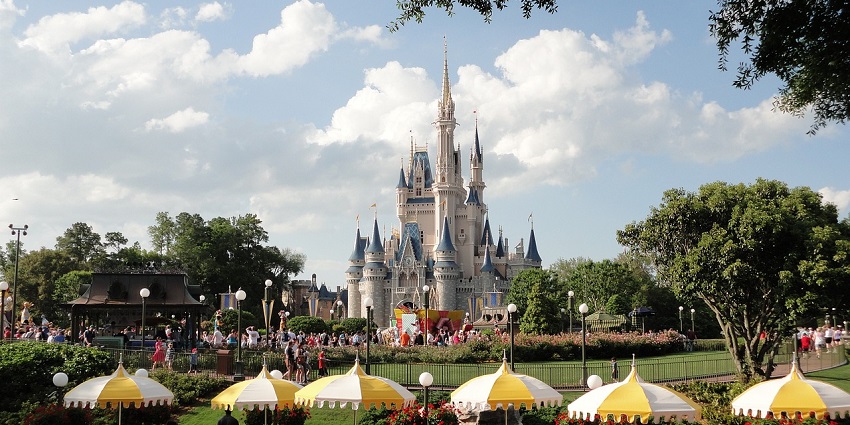 An image of Disneyland’s iconic castle with colourful decorations under a clear blue sky