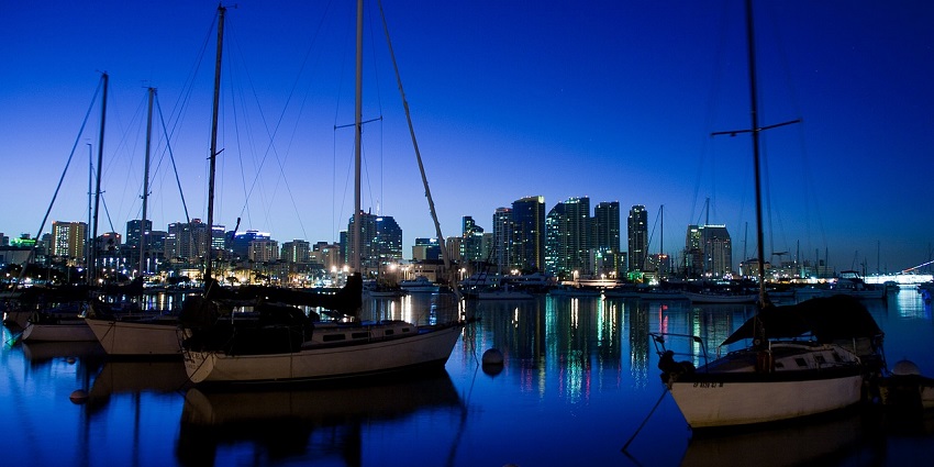 An image of San Diego Bay with calm water, boats, and the city skyline in the background