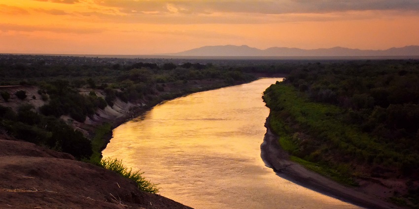 Omo River is flowing through a valley in Ethiopia featuring a beautiful and vibrant sunset