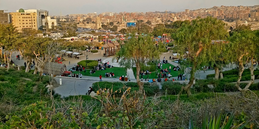 A few visitors are roaming inside the Al-Azhar Park, featuring a beautiful fountain.