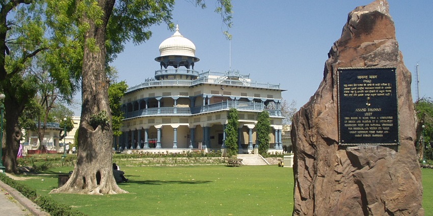 An image of Anand Bhawan building flanked by a large stone structure.