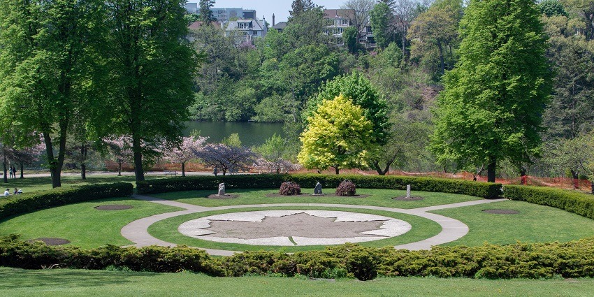 A calm view of High Park covered with grass carpet and a maple leaf structure, one of the best things to do in Toronto.