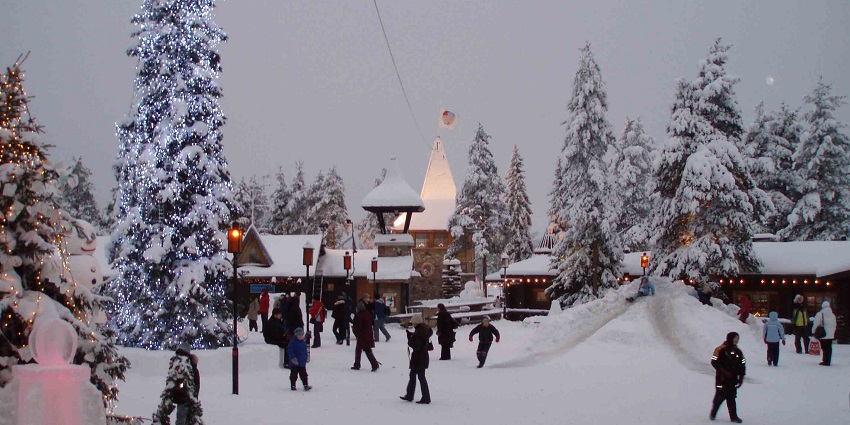 Santa Claus Village covered in snow and decorated during winter with people exploring.