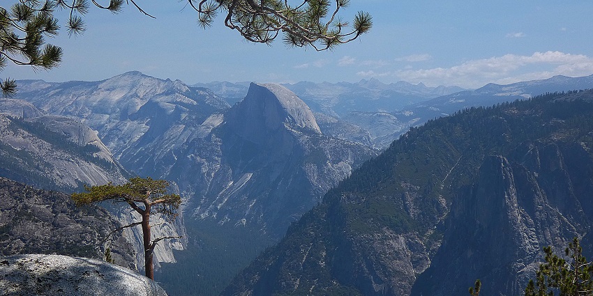 An image of Yosemite National Park’s stunning granite cliffs, trees, and clear blue sky in the background