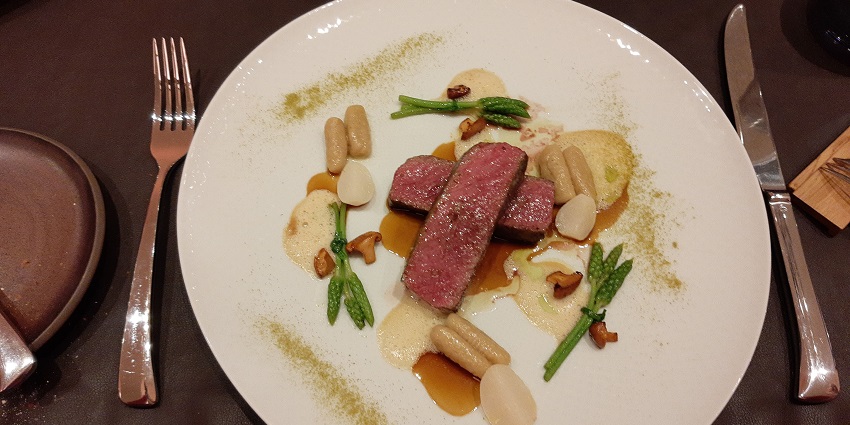 May deer served with herbs and spices on a white plate with cutlery on the table