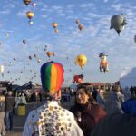 An image of a vibrant scene at the Albuquerque Balloon Fiesta with colourful hot air balloons soaring