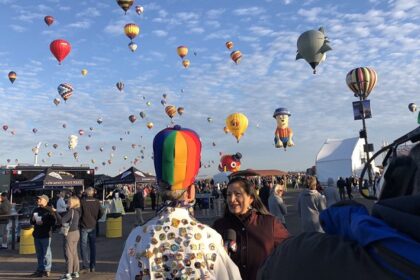 An image of a vibrant scene at the Albuquerque Balloon Fiesta with colourful hot air balloons soaring