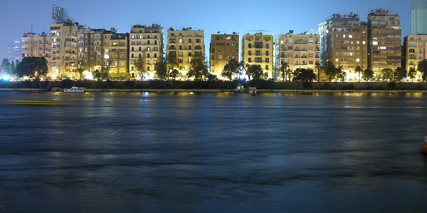 Nile River at night with lit-up buildings in the background and distant boats parked