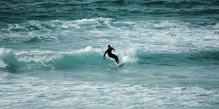 An enchanting image of a lone surfer on Fistral Beach enjoying surfing on the waves.