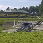 A historical view of the cannon at Old Fort Erie, set on green grass with trees and cloudy skies.