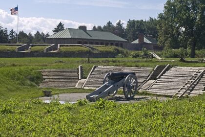 A historical view of the cannon at Old Fort Erie, set on green grass with trees and cloudy skies.