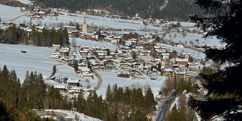 A scenic view of Gerlos Alpine Road, surrounded by lush green mountains and a misty atmosphere.