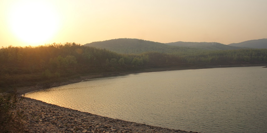 An image of a large bridge over a river in Ghatshila including rapids and debris.