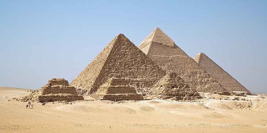 Several pyramids of various sizes are placed next to each other in a sandy desert.