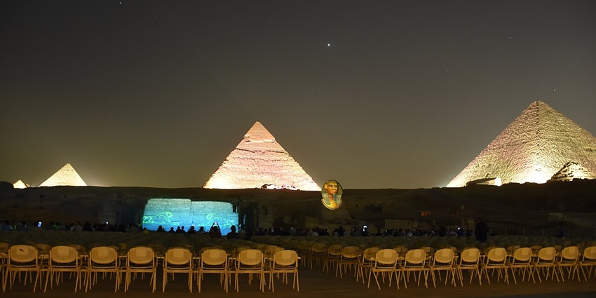 Sound and light show of Giza pyramids at night with bright projections and seating area.