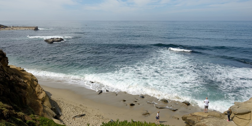 A hilltop picture of a scenic beach in California with views of blue waters and golden sand