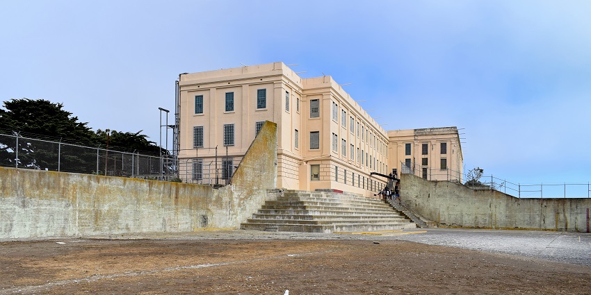 View of Alcatraz recreation yard with stairs leading to the entrance and a bird on the ground area