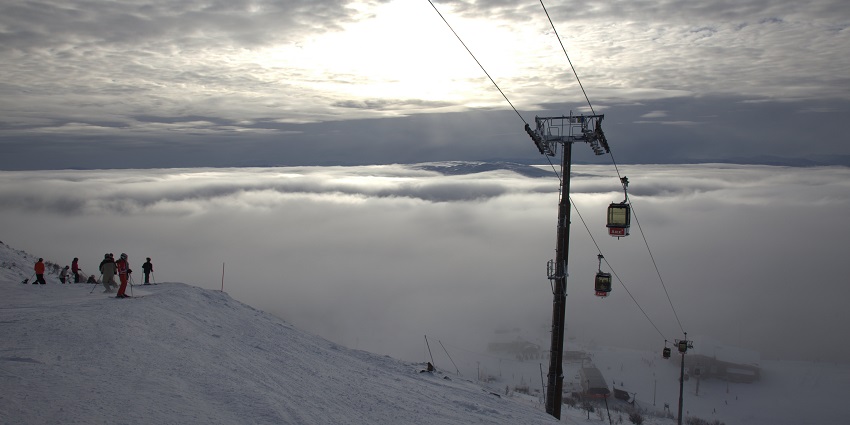 Gondola ride cabins at Mount Areskutan with a group of people skiing on snow-covered land