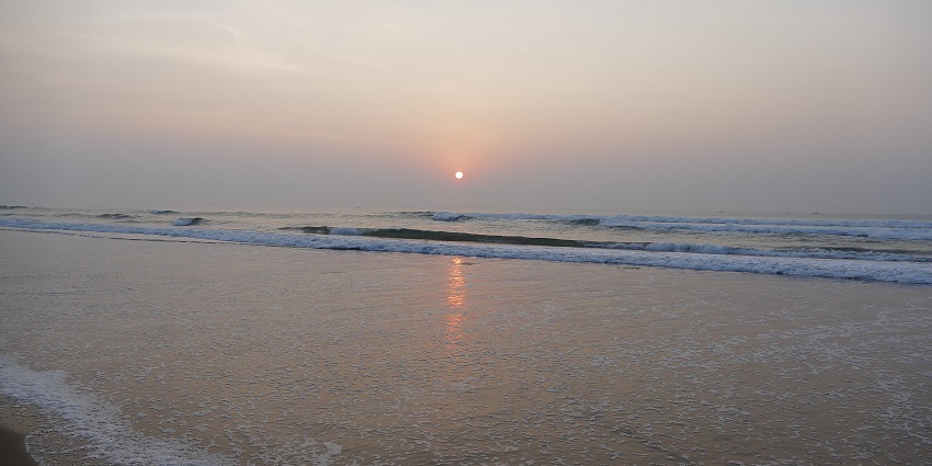 A panoramic view of Gopalpur Beach shows makeshift stalls selling accessories and food.
