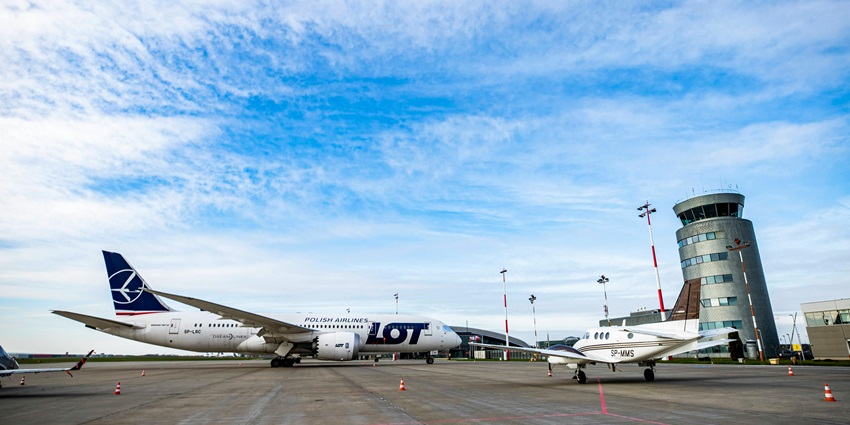 A white passenger plane and a small jet beside it with a circular tower visible nearby.