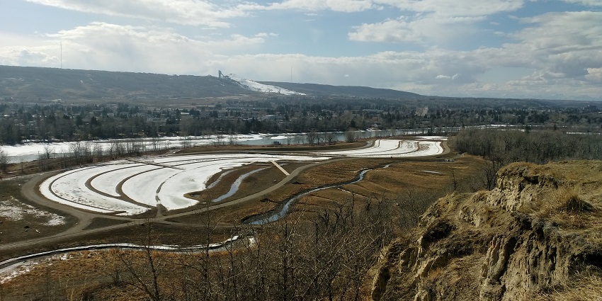 Winsport Canada Olympic Park with dried winter trees and grass, snow and a river