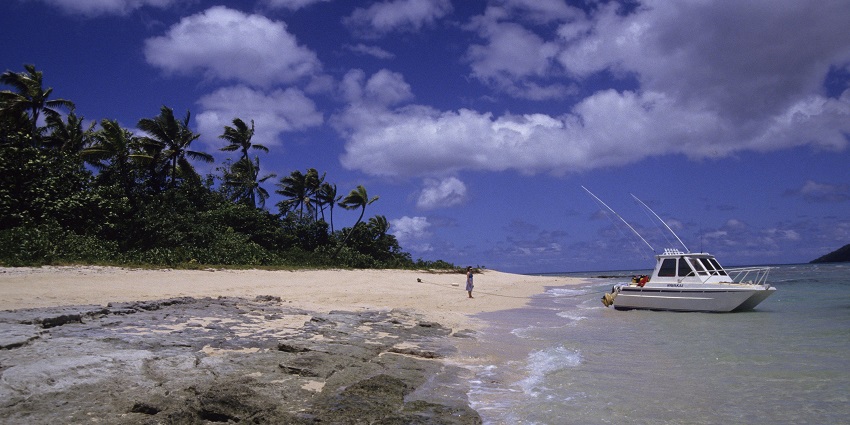 On a sunny day, a small speed boat docked at a beach in Bouma National Heritage Park.