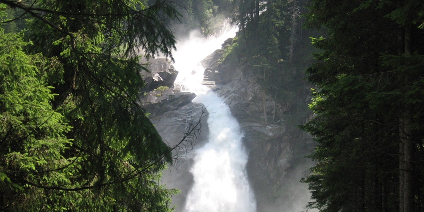 A picture of Krimml Waterfalls cascading down the mountainside in a lush green forest.