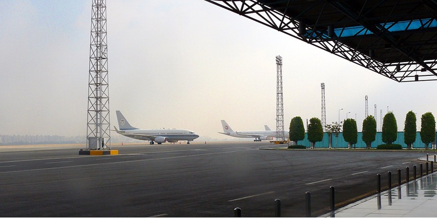 At a distance, several aeroplanes can be seen standing at an International Airport.