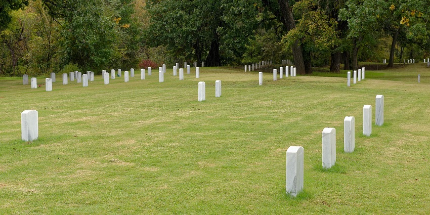 Fort Sill, Oklahoma, showcasing rows of gravestones against a backdrop of trees and clear skies