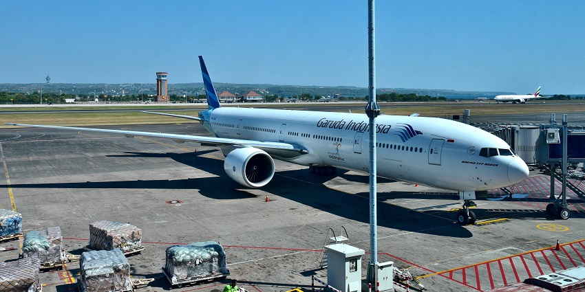 A Garuda Indonesia plane parked near a terminal building at Ngurah Rai International Airport.
