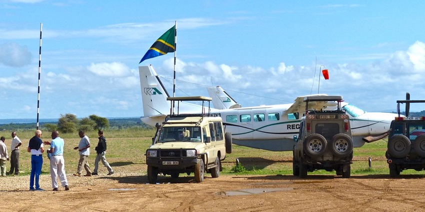 A glimpse of safari vehicles parked next to an aeroplane and people in the Seronera airstrip.