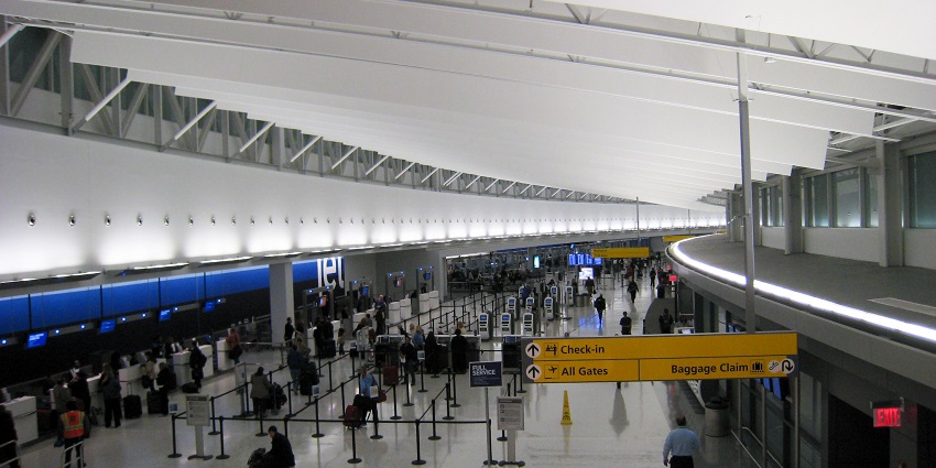 A modern interior of JFK Terminal 5 showing the ticketing and check-in area with high ceilings.