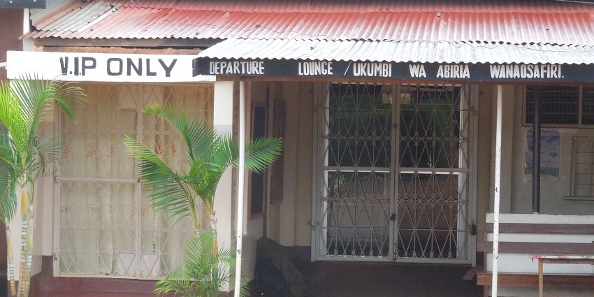 Entrance of Kigoma airport departure and VIP terminal with signages, plants and a table