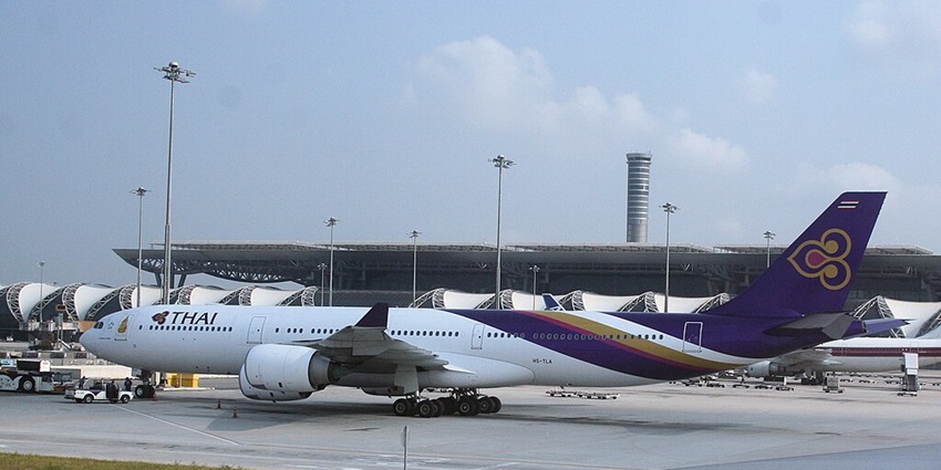 A Thai Airways flight parked near a runway at Suvarnabhumi Airport in Bangkok, Thailand.