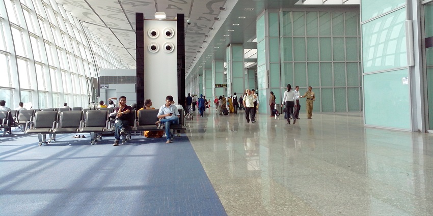 Crowded airport terminal buzzing with travellers navigating, waiting, and checking in.