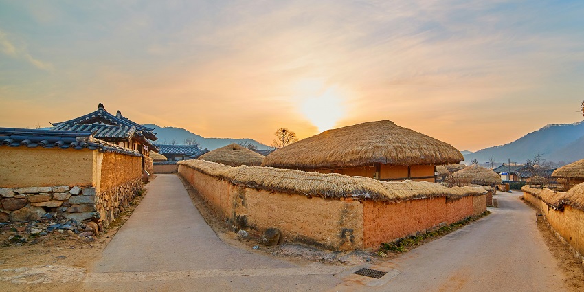 Image of a village huts in Tanzania with ;ush green trees around and golden sand