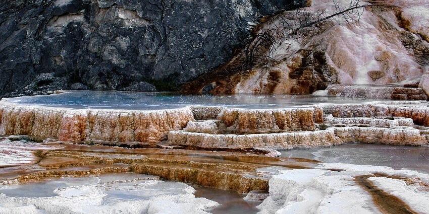 An image showing a hot spring with a beautiful scenic backdrop of rocky formations.