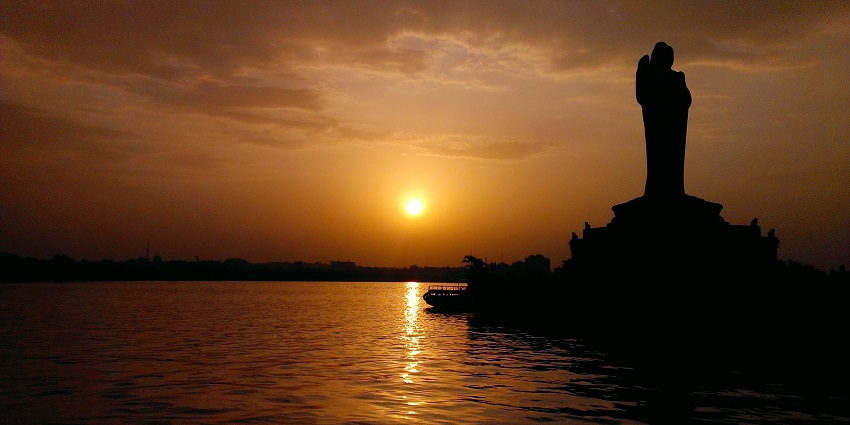 A Picturesque lake with an iconic Buddha statue and boating activities.