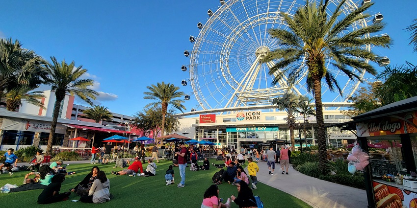 ICON Park complex with people sitting on the lawns and the observation wheel visible