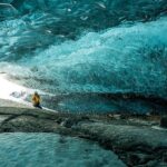 An image of Ice formations inside a cave with sparkling frozen stalactites and blue ice walls.