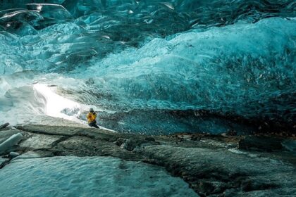 An image of Ice formations inside a cave with sparkling frozen stalactites and blue ice walls.