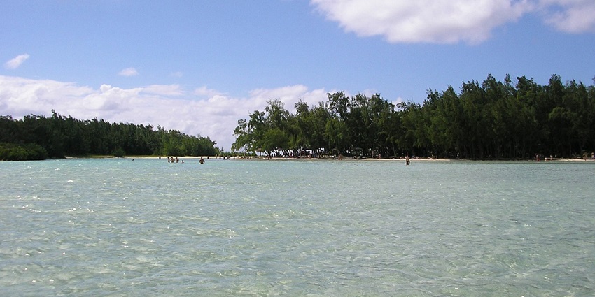 Ile aux cerfs with small islands, clear water, distant people in the water and greenery.