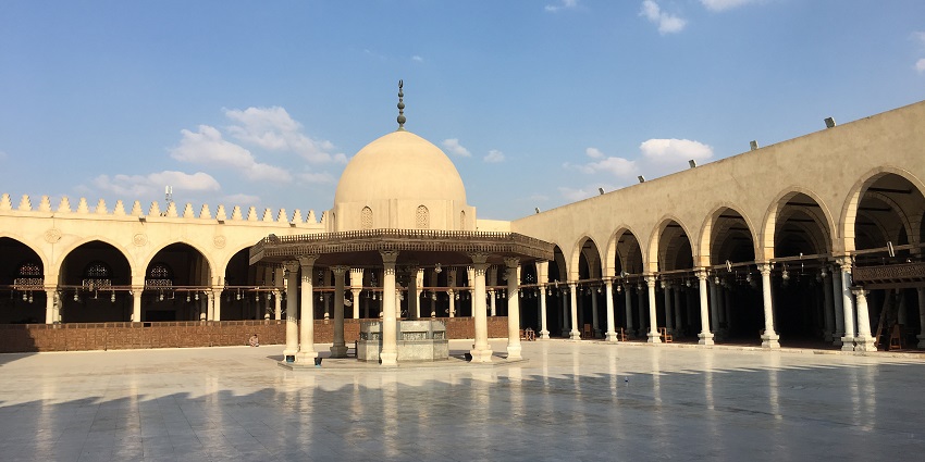 A massive inside area of a Mosque in Islamic Cairo featuring a dome in the middle.
