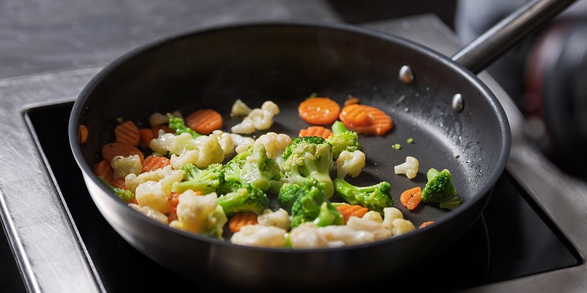 Colorful vegetables, broccoli, cauliflower, and carrots, sizzling in a hot pan. A culinary preparation scene