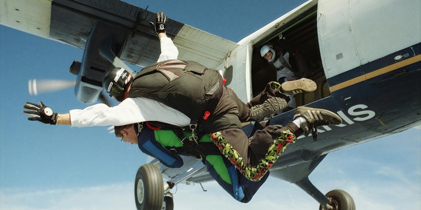 A picture of a skydiver leaping from an aeroplane above the scenic landscape.