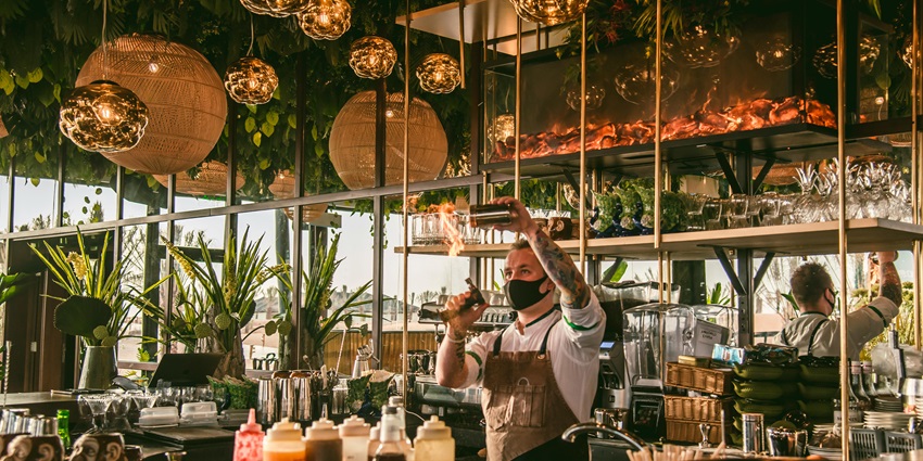 Bartender playing tricks and different bottles on the counter in a decorated garden